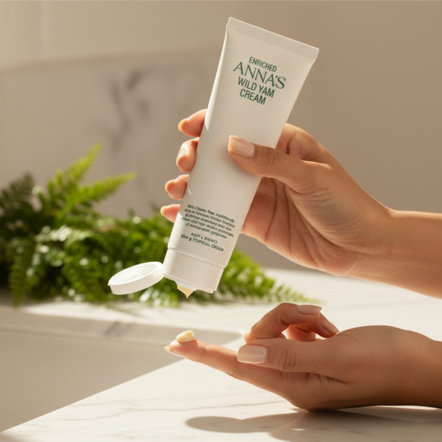 A close-up of a person squeezing a small dollop of Anna's Wild Yam Cream onto their index finger from a white tube.