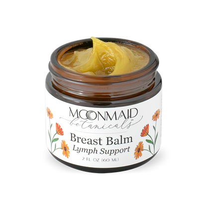 An open jar of Moonmaid Botanicals Breast Balm showing a smooth, golden-yellow swirled herbal salve texture optimized for lymph support.