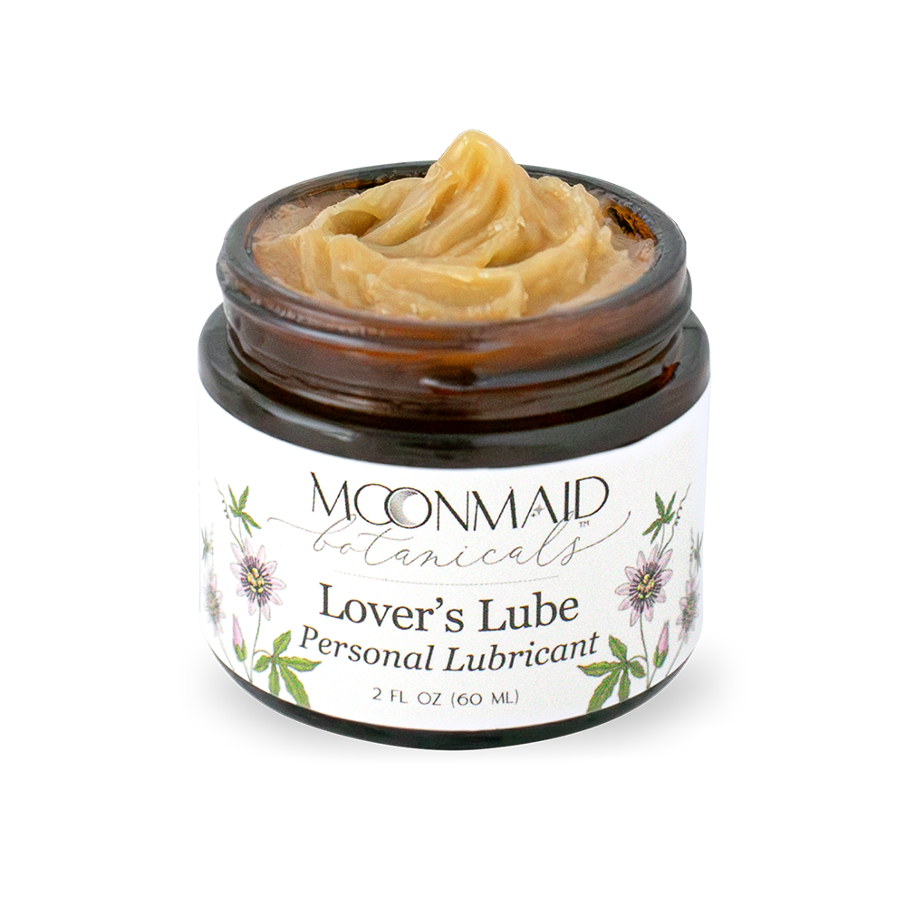 Open jar of Moonmaid Botanicals Lover's Lube showing the golden-amber, smooth ointment texture of the natural personal lubricant.